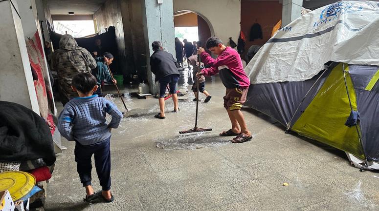 نازحون يتفقدون خيامهم التي غمرتها مياه الأمطار في فناء مدرسة بيت المقدس في خان يونس، جنوب قطاع غزة