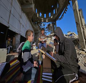 مواطنون، بينهم أطفال، يتعبدون ويتلون القرآن الكريم خلال شهر رمضان بين أنقاض مسجد الألباني الذي قصفه الاحتلال في خان يونس