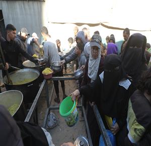 نازحون يتجمعون للحصول على وجبة إفطار رمضان مجانية من إحدى الجمعيات الخيرية في مخيم النصيرات، في ظل محدودية المساعدات الإنسانية وأزمة الغذاء المستمرة في القطاع