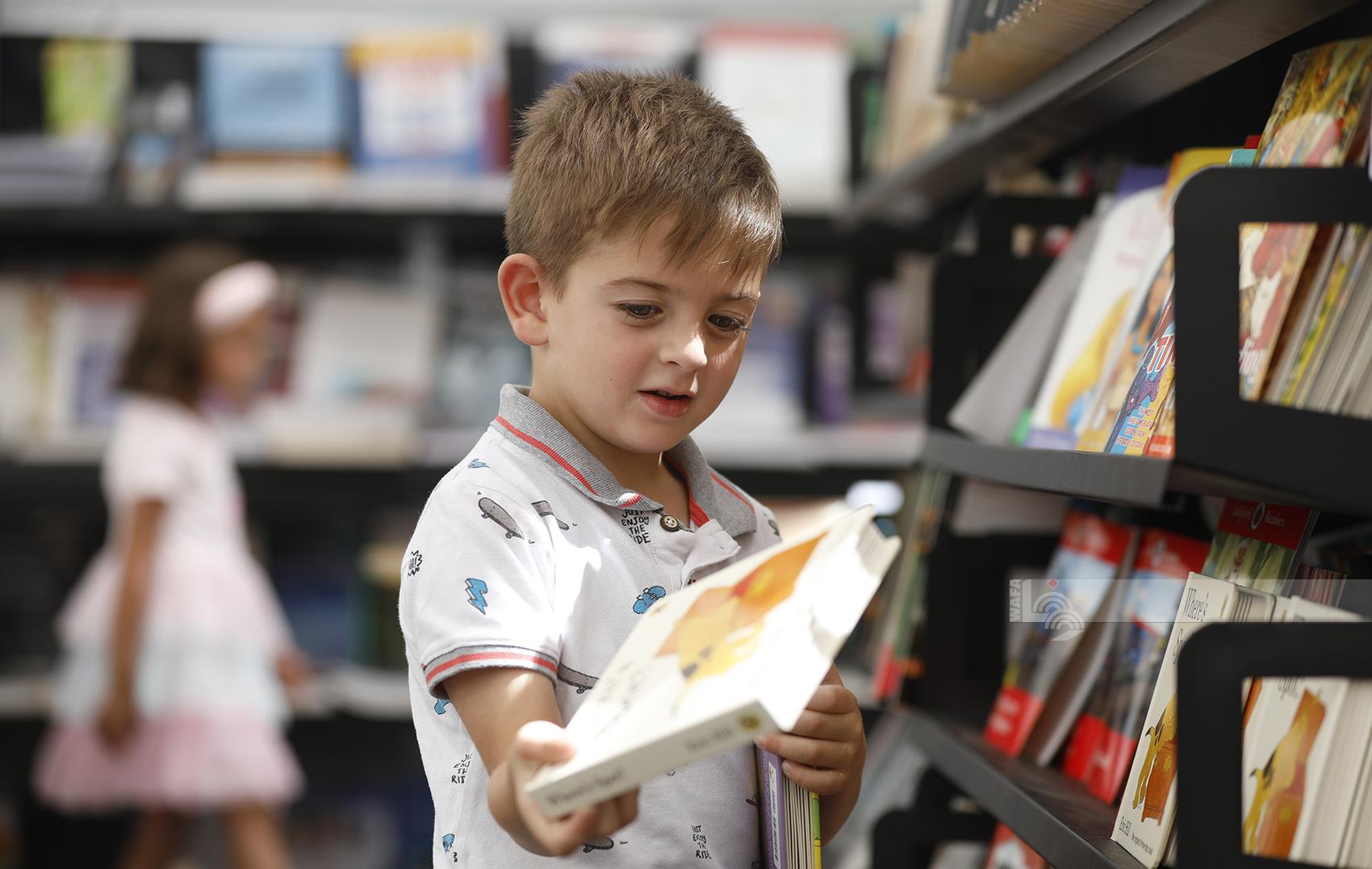 طفل يقتني مجموعة من كتب الأطفال في معرض فلسطين الدولي الثالث عشر للكتاب (تصوير: حذيفة سرور/وفا)